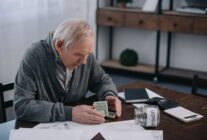 senior man sitting at table with money paperwork 2022 12 16 18 48 27 utc 1024x683